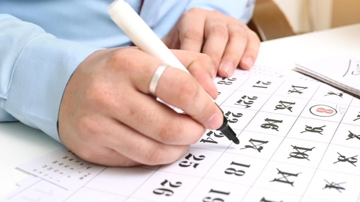 Un hombre tacha días en un calendario.