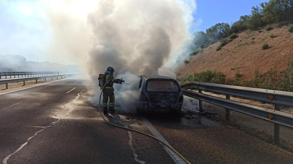 Un bombero sofoca el incendio originado en el turismo, en la autovía A-11