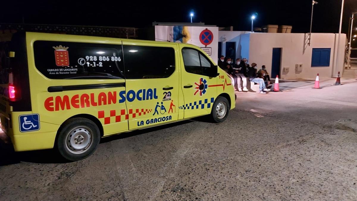 Un vehículo de atención social de Emerlan esta madrugada en La Graciosa. Al fondo, los migrantes.