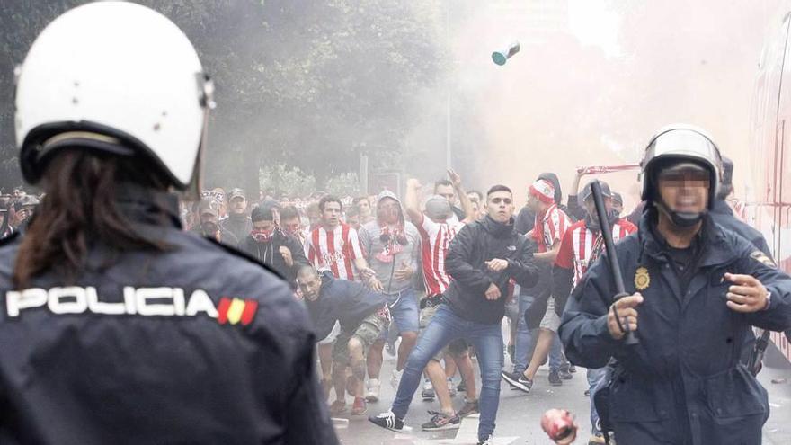 Un momento de los altercados, con objetos volando hacia los policías junto al autobús del Sporting.