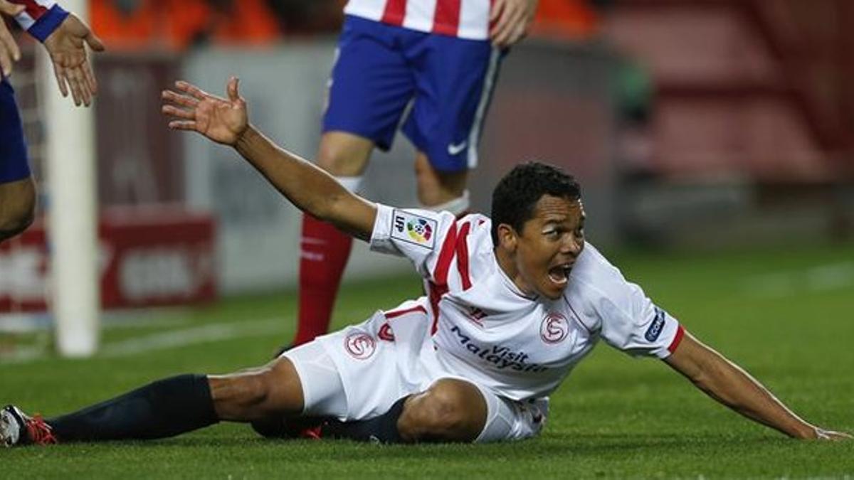 El delantero del Sevilla Bacca protesta tras una entrada durante el partido contra el Atlético