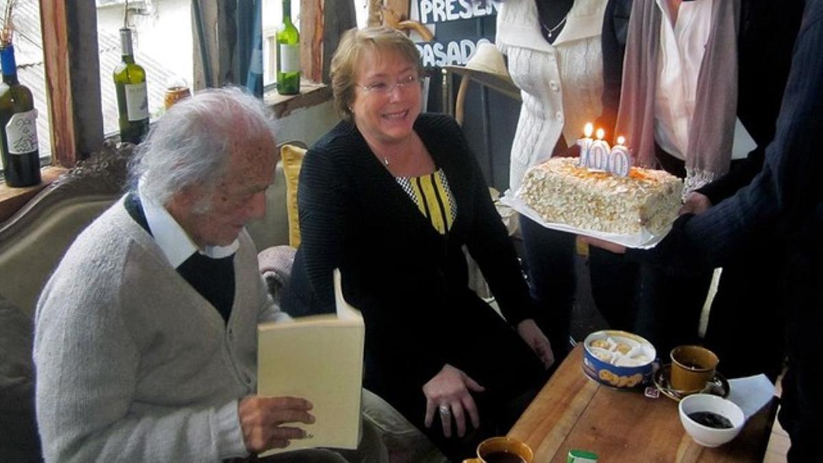 Nicanor Parra recibe el pastel de su 100º aniversario, junto a la presidenta chilena Michelle Bachelet, este viernes.