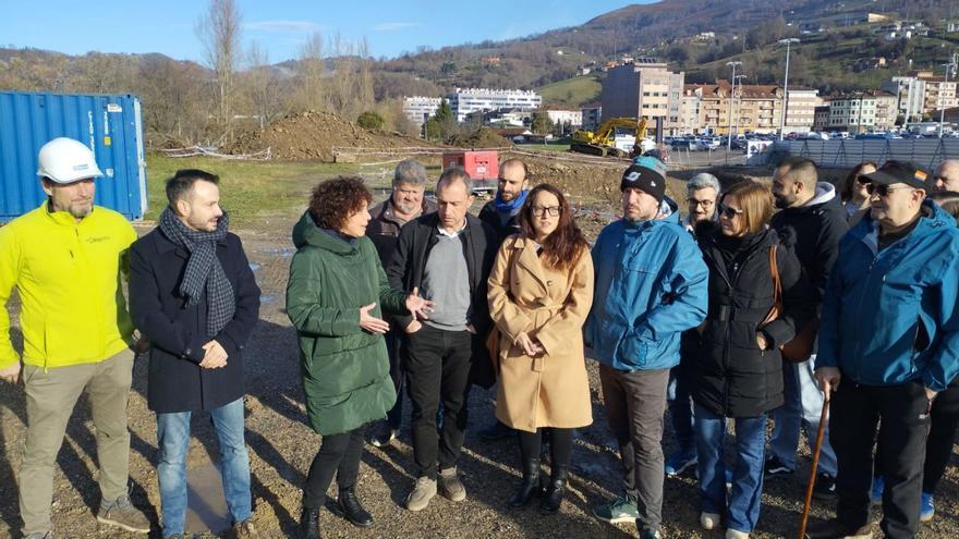 Jacoba García, en el centro, con abrigo verde, conversa con Ovidio Zapico, con la obra de los pisos detrás.  | M. Á. G.