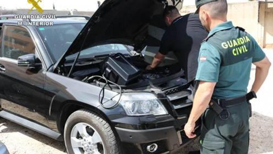 Un agente junto a un técnico que revisa uno de los coches intervenidos.