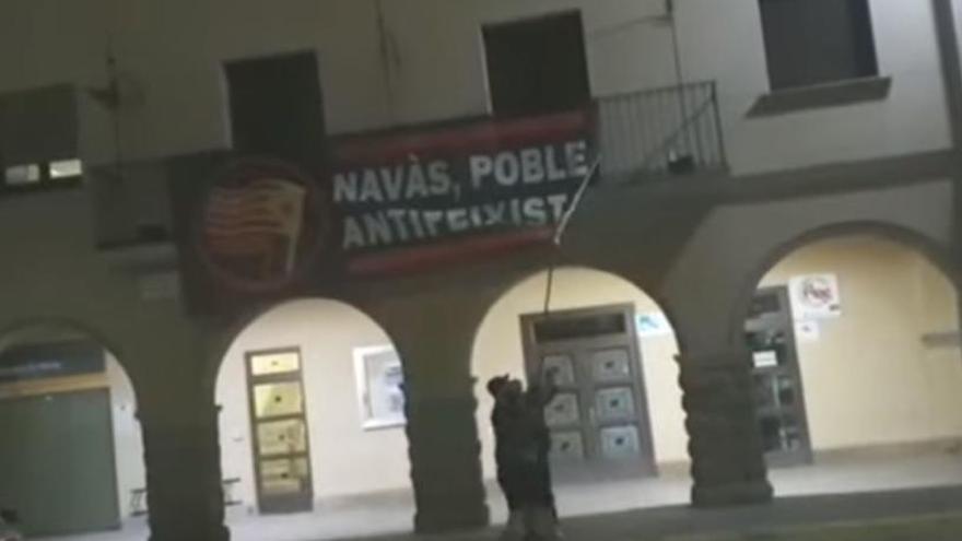 Un dels acusats traient la pancarta enganxada a la façana de l&#039;Ajuntament de Navàs