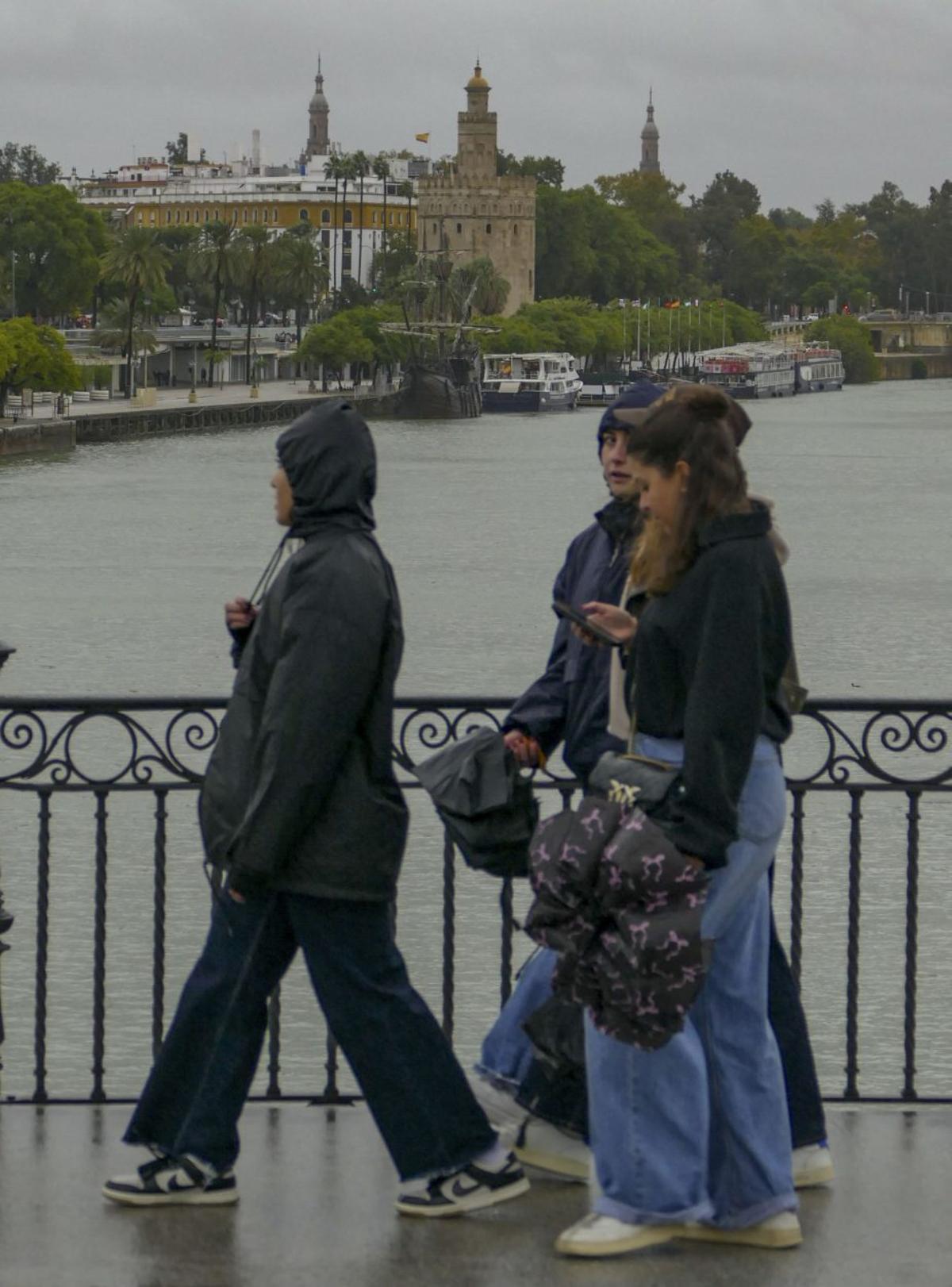 Personas junto al Guadalquivir crecido en Sevilla capital.
