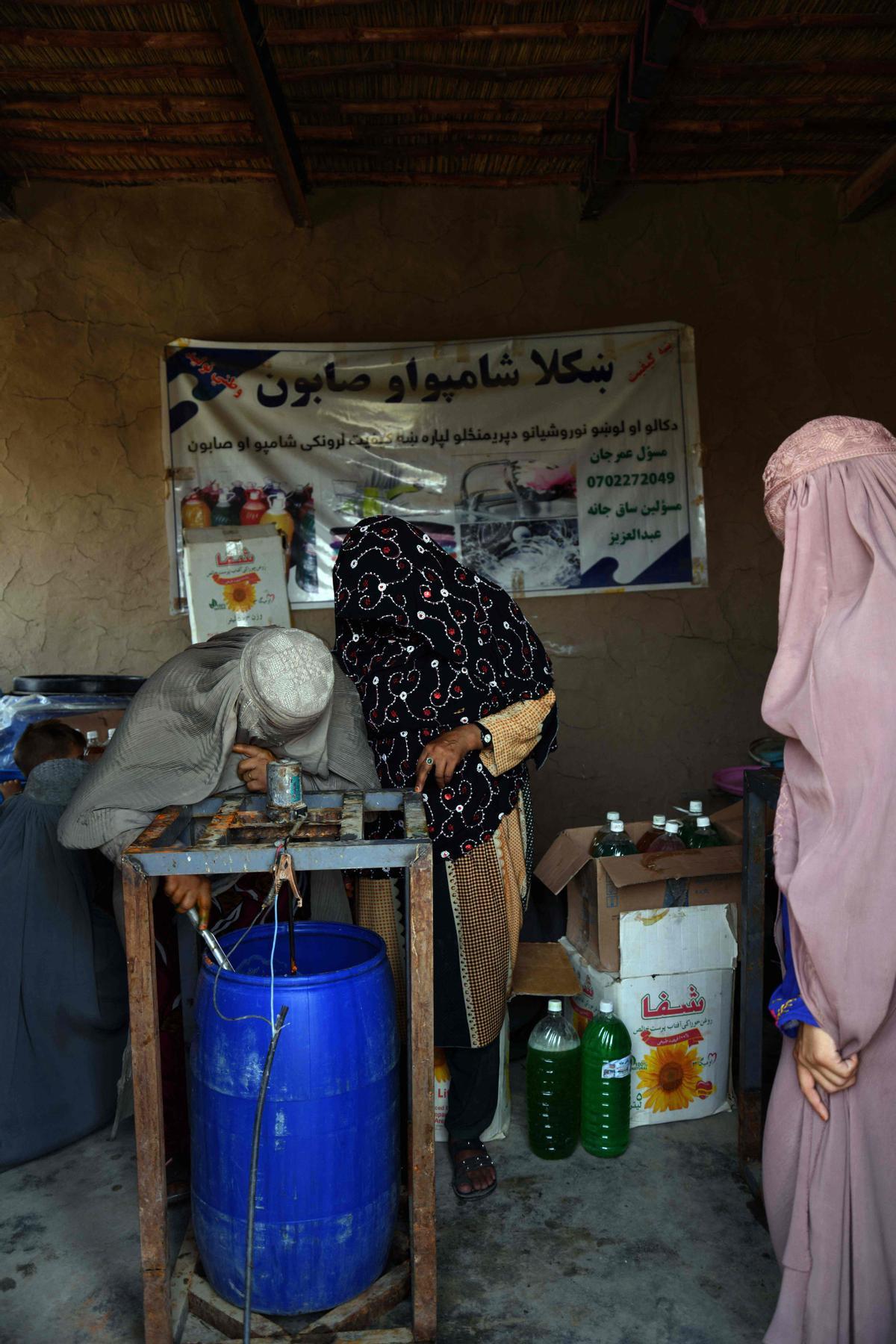 Afganas con burka trabajando en una fábrica de jabón y ropa en Kandahar