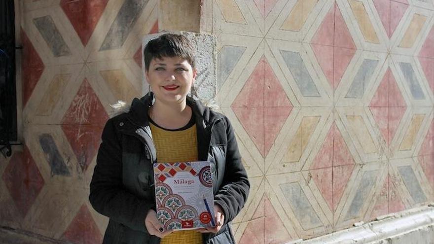 Marina de Rojas, con su libro de Málaga para colorear, delante de las pinturas murales de San Juan.