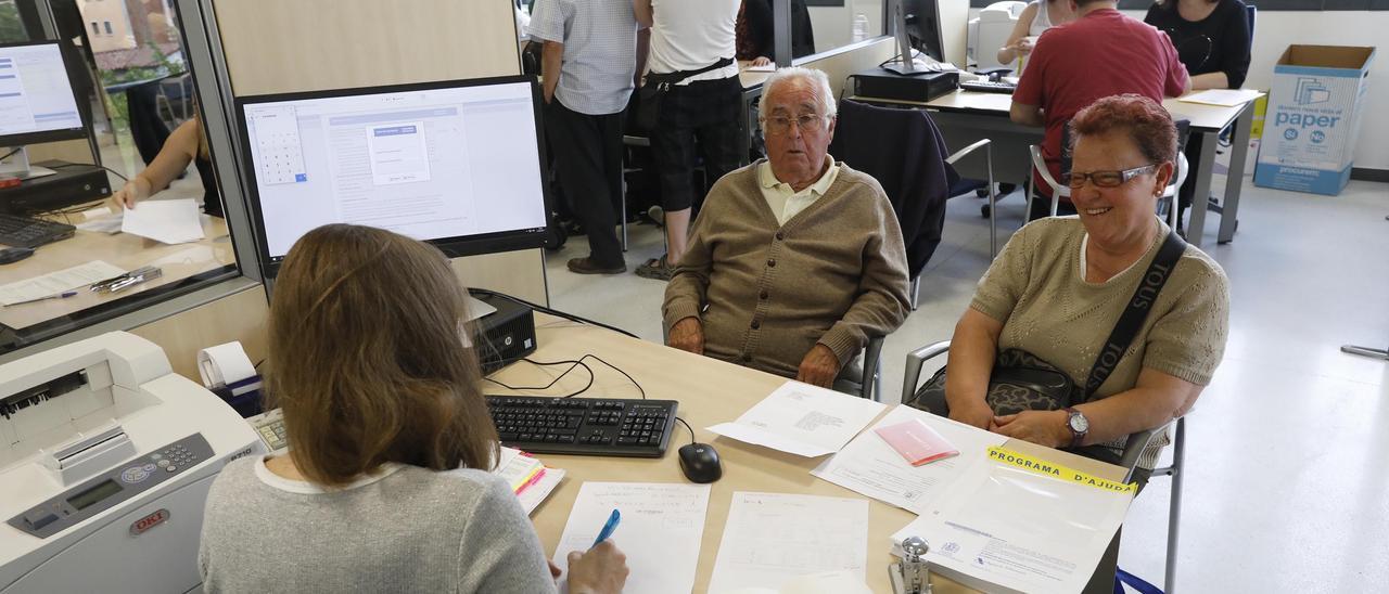 Dues persones a les instal·lacions de l’Agència Tributària a Girona juntament amb una treballadora.
