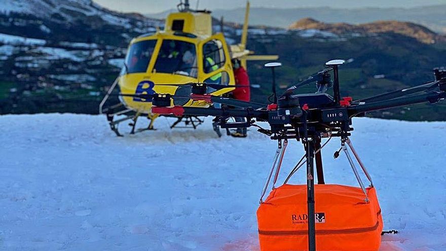 En primer término, el georradar cargado en el dron y, al fondo, el helicóptero de Bomberos de Asturias desde el que se pilotó