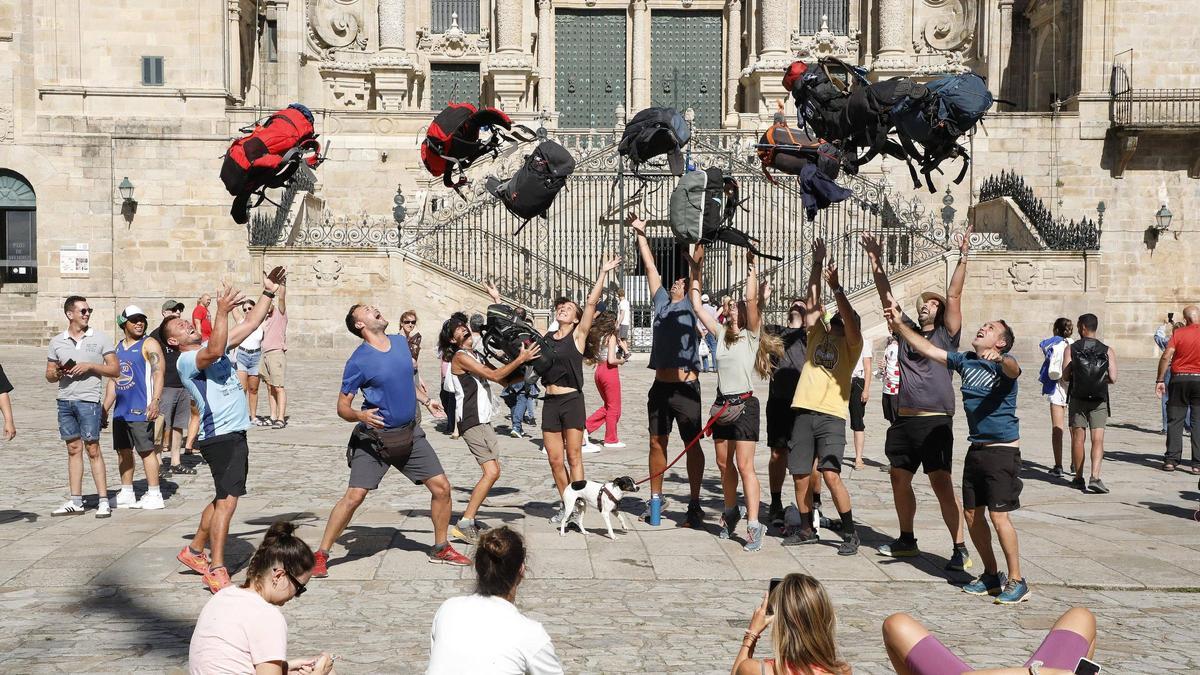 Unos peregrinos arrojan sus mochilas al aire en la Praza do Obradoiro tras terminar el Camino.