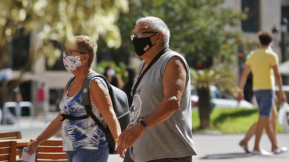 Un par de peatones con mascarilla pasean por las calles de València.