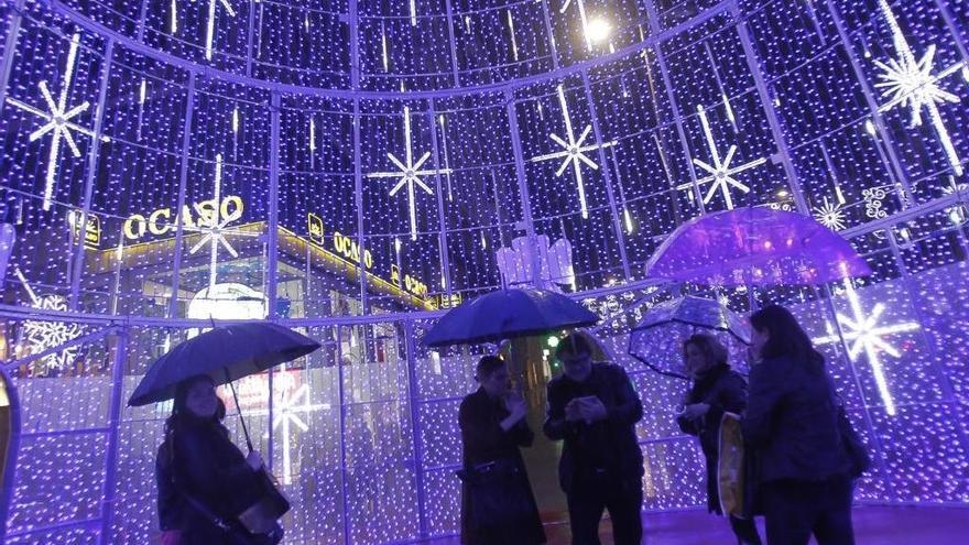 Viandantes con paraguas en el interior del árbol de Navidad de Porta do Sol. // Adrián Irago