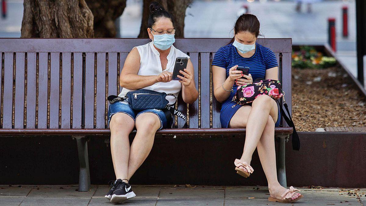 Dos mujeres con mascarilla en un banco de la capital chicharrera.