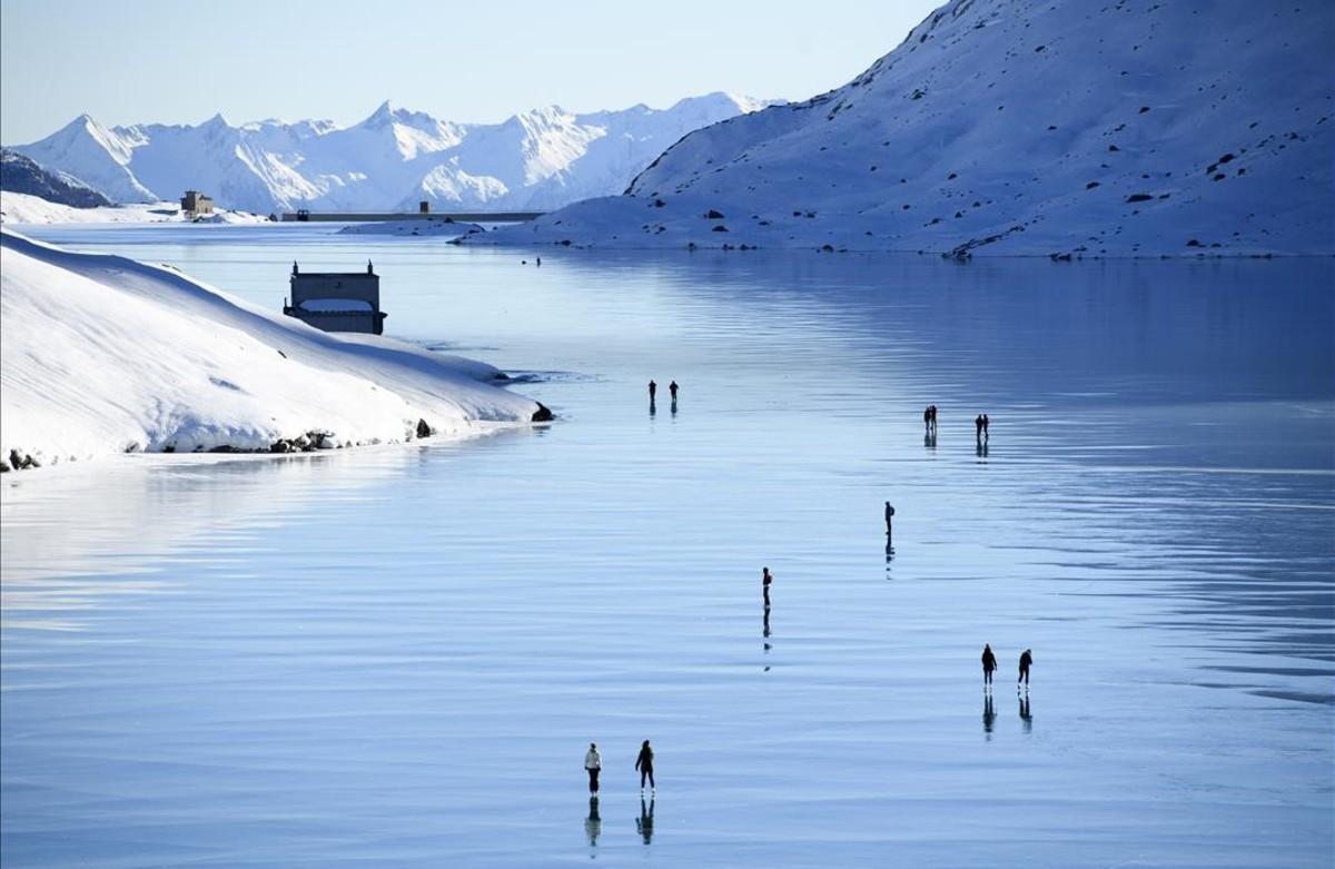  Visitantes disfrutan de un día soleado en el hielo negro del Lago Bianco, en Poschiavo, Suiza.