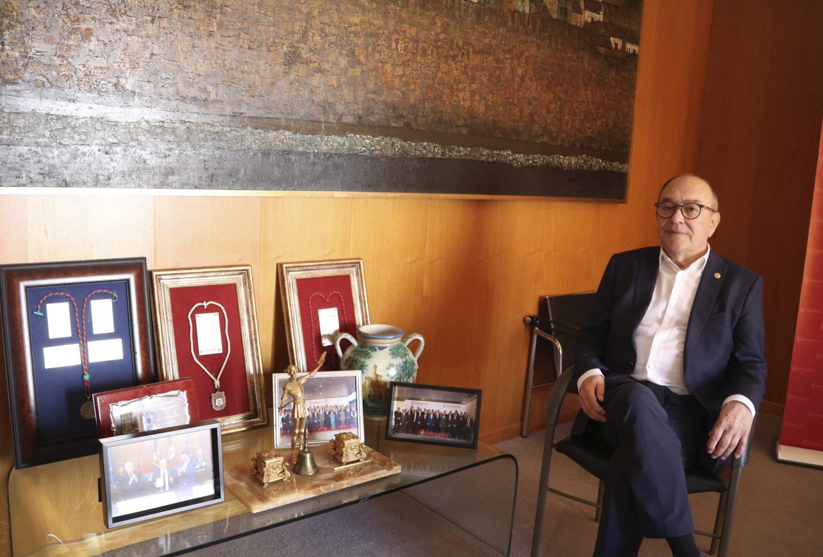 Enrique Oliveira en su despacho junto a una mesa con fotografías y trofeos.