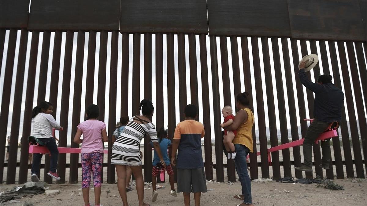 Niños migrantes jugan ante el muro que divide la frontera entre EEUU y México, en Ciudad Juárez.