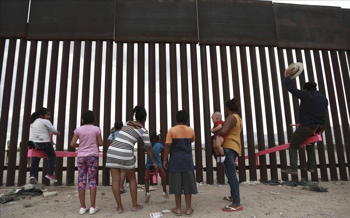 Niños migrantes jugan ante el muro que divide la frontera entre EEUU y México, en Ciudad Juárez.