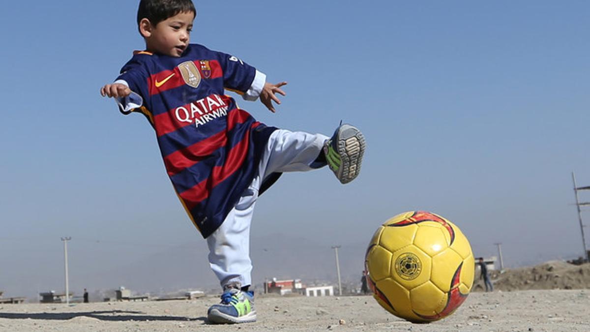 El pequeño Murtaza Ahmadi, ataviado con la camiseta del Barça firmada por Messi, su ídolo, juega con un balón en Kabul, este viernes.