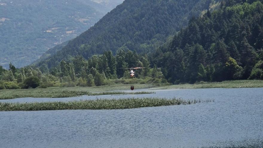 Un helicóptero carga agua en el embalse de Plandescun para combatir el incendio de Plan