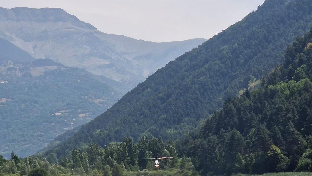 Un helicóptero carga agua en el embalse de Plandescun para combatir el incendio de Plan