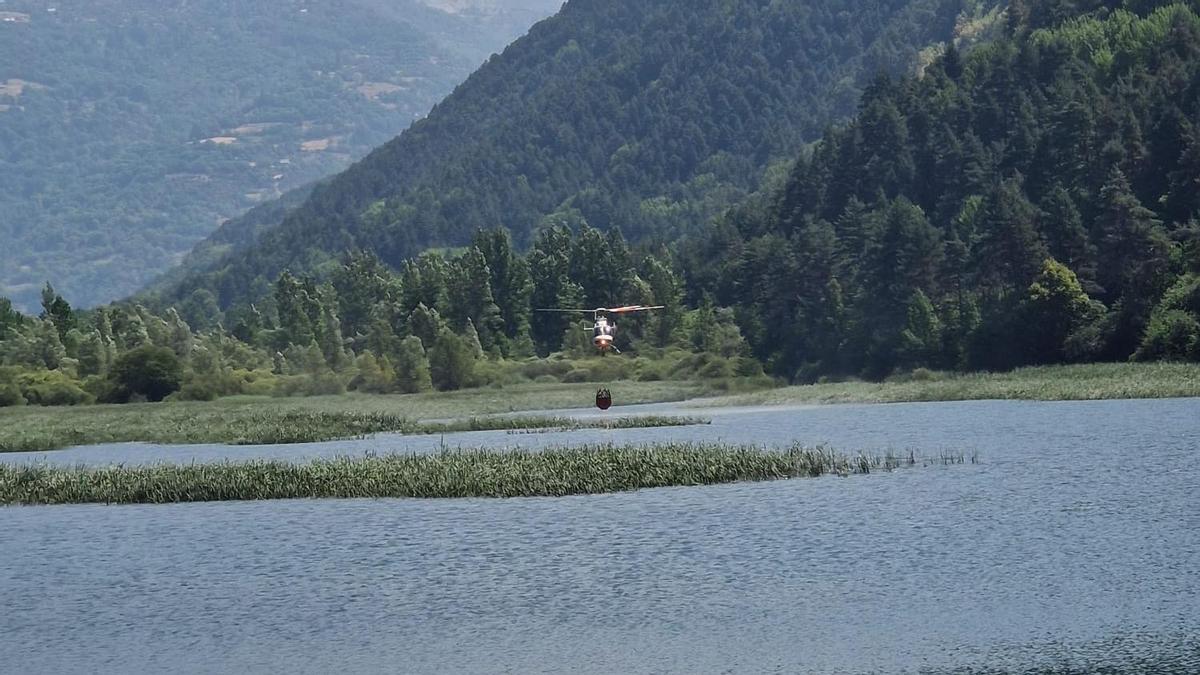 Un helicóptero carga agua en el embalse de Plandescun para combatir el incendio de Plan
