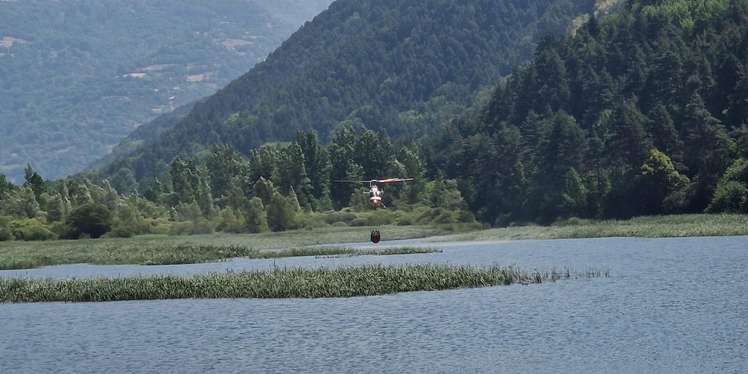 Un helicóptero carga agua en el embalse de Plandescun para combatir el incendio de Plan