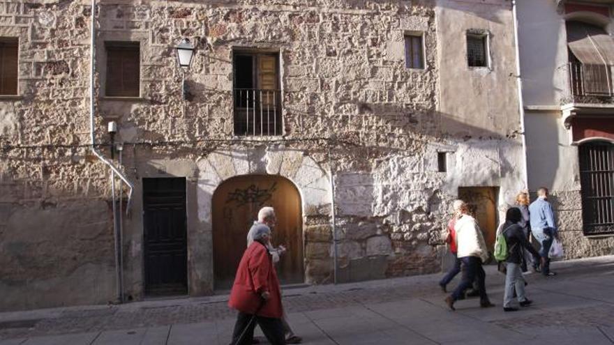 Viandantes pasean por el casco histórico, que registra varias edificaciones en estado deficiente o de ruina.