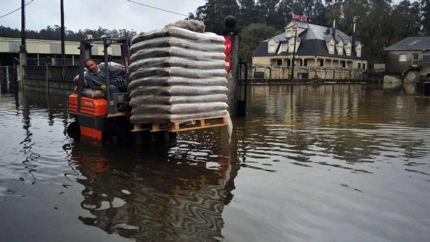 Un operario de Comercial Vilanoviña transporta sacos de &quot;pellets&quot; desde el almacén que quedó inundado debido a la crecida del río Umia. // Iñaki Abella