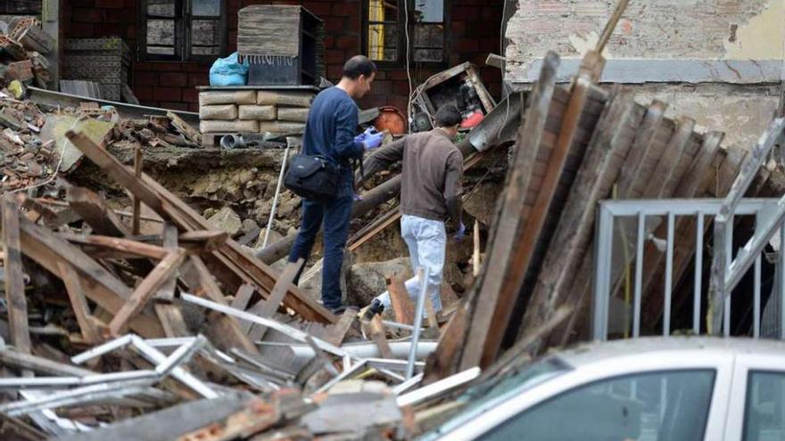 Dos agentes inspeccionan la casa derrumbada en la mañana de ayer.