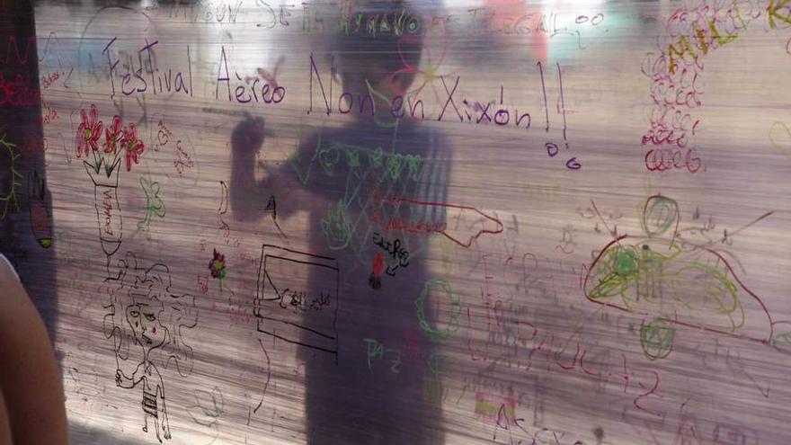 Un niño dibuja en la pancarta del festival alternativo &quot;Folixa pola paz&quot;, celebrado en el Pueblu d&#039;Asturias.