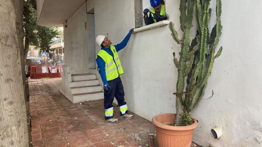 Dos operarios arreglan la fachada de uno de los locales del entorno del faro.