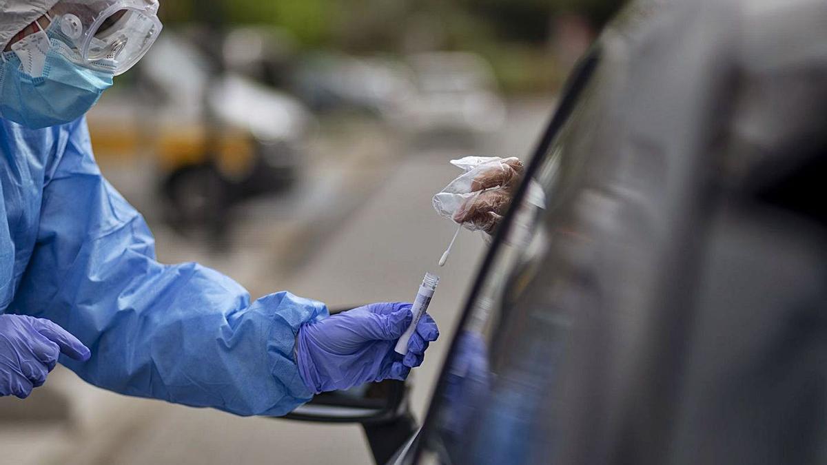 Un sanitario realiza el test del COVID a un conductor en las inmediaciones del hospital. | Emilio Fraile