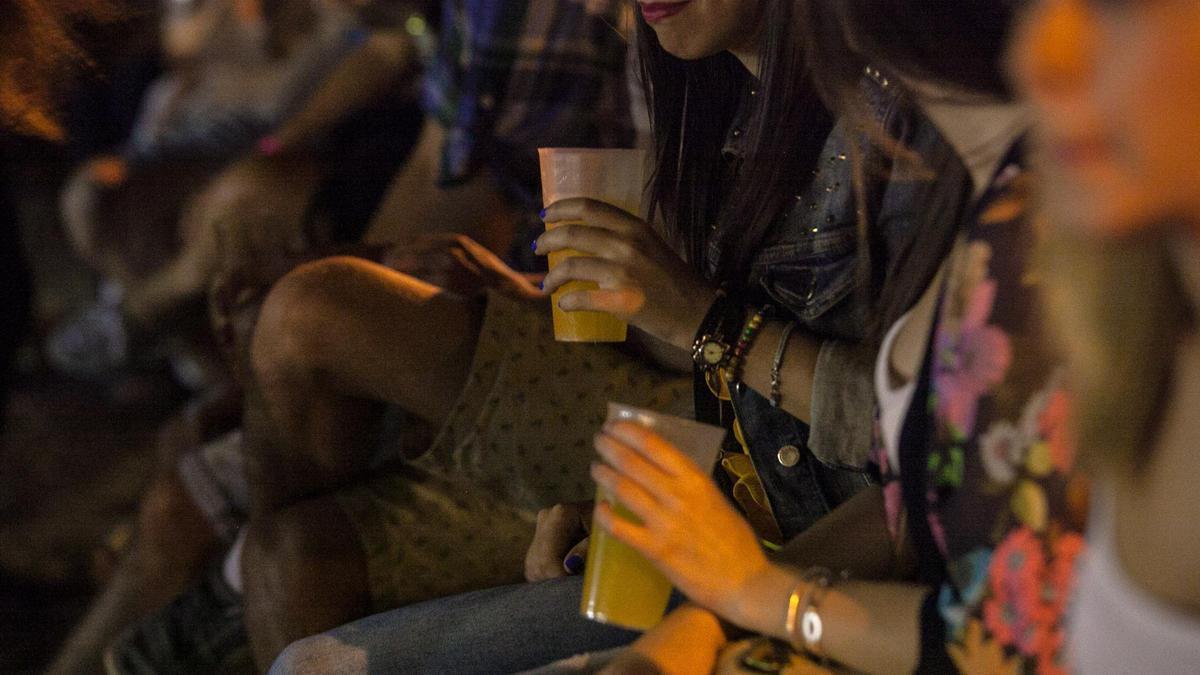 Un grupo de jóvenes sujetan unos vasos con refresco de naranja en una fiesta, en una imagen de archivo.