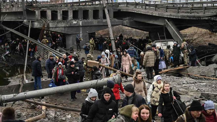 Un numeroso grupo de gente cruza un puente destruido en su camino por salir de la ciudad de Irpin, al noroeste de Kiev.