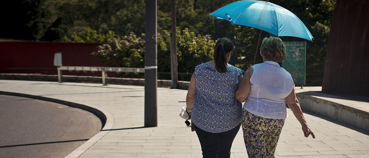 Dos mujeres se protegen del calor con un paraguas en Ourense en julio de 2020. |   // BRAIS LORENZO