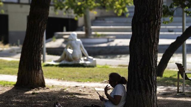 Una ciutadana aprofita les ombres del parc de l’Espanya Industrial, que actua com a refugi climàtic. | MARC ASENSIO CLUPÉS