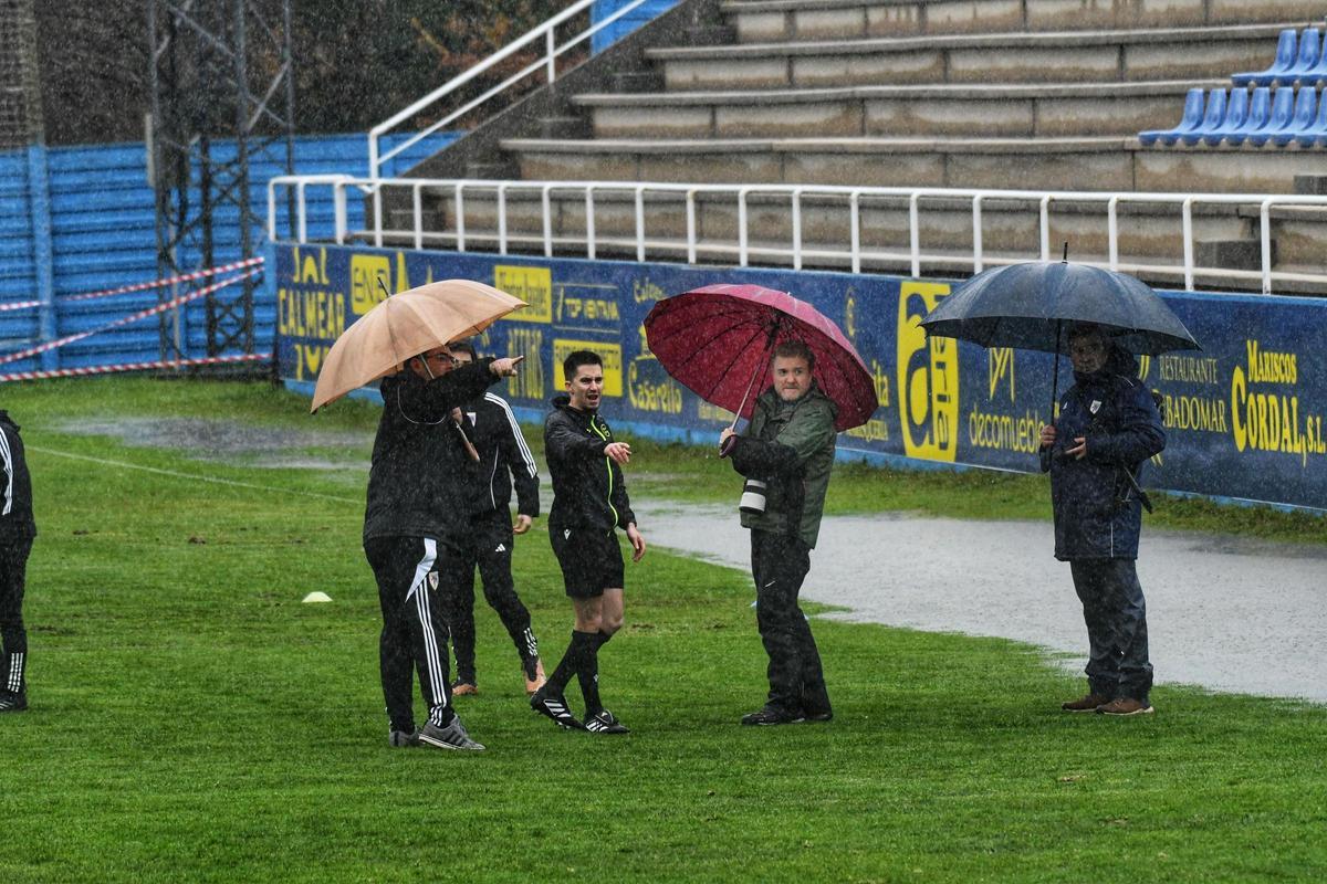 El árbitro del Cambados-Compostela revisa el estado del campo junto a responsables de ambos clubes.