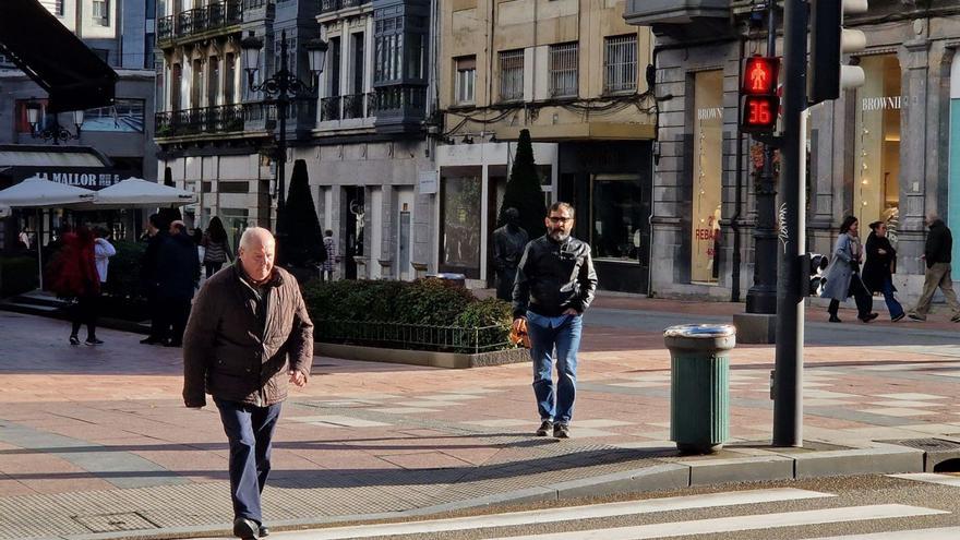 Peatones esperando para cruzar en el semáforo de la confluencia de las calles Uría y Milicias Nacionales, con la nueva cuenta atrás en funcionamiento. | LNE