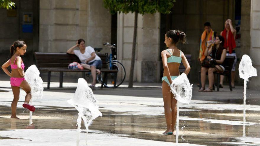 Dos niñas se refrescan ayer en una fuente de Alicante, mitigando los 37 grados de máxima