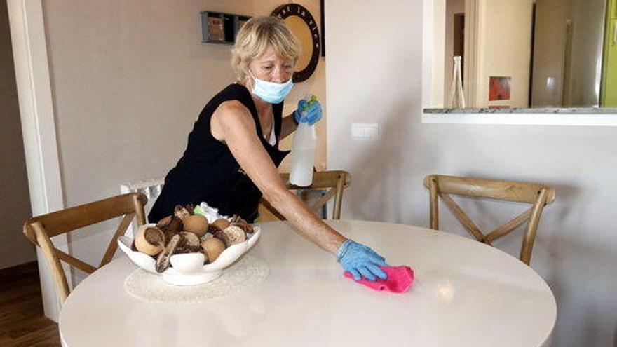 Una treballadora neteja la taula del menjador d&#039;un apartament de Sant Antoni de Calonge