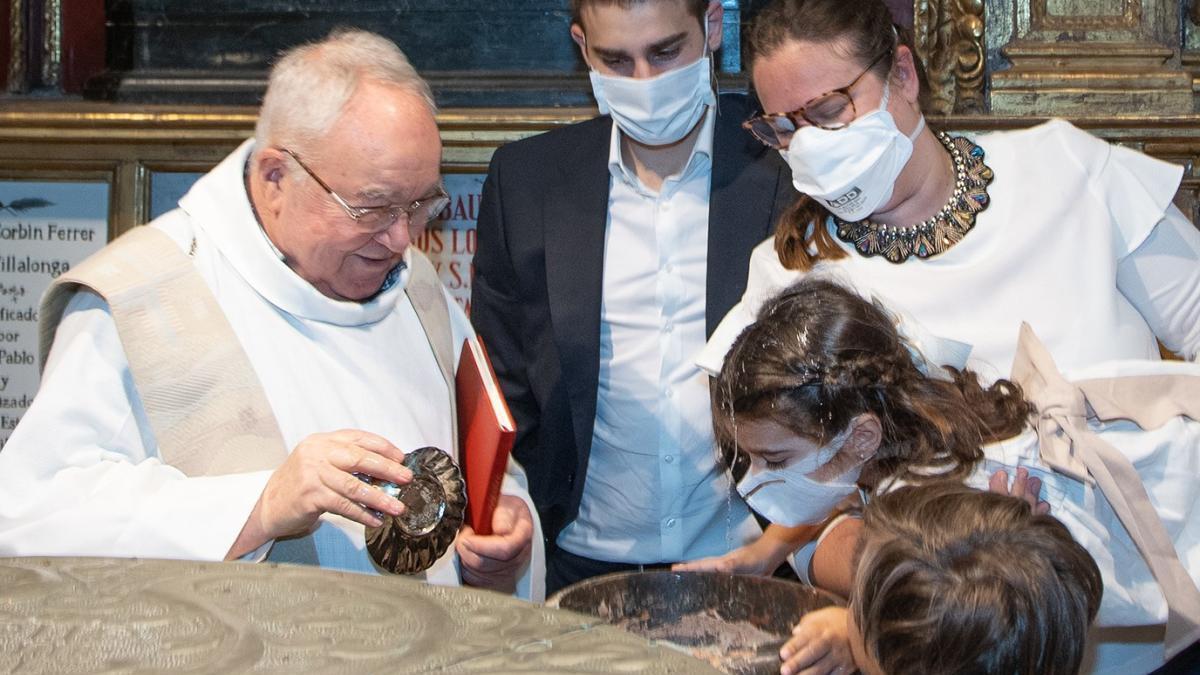 El párroco administra las aguas a la niña Carlota.