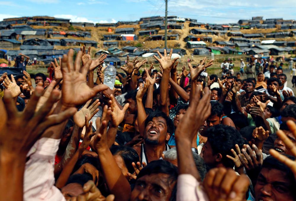 Rohingya refugees stretch their hands to receive ...