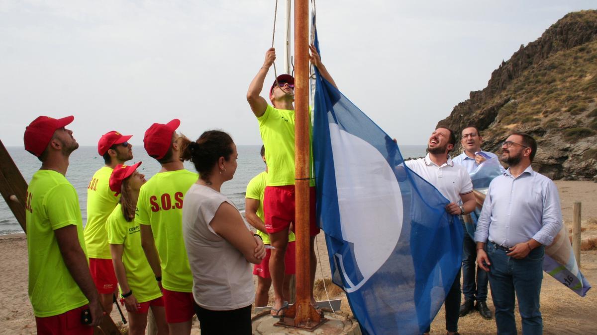 Isabel Casalduero, Francisco Morales, Diego José Mateos y José Luis Ruiz, contemplan como uno de los socorristas de la cala de Calnegre iza la Bandera Azul, este lunes.