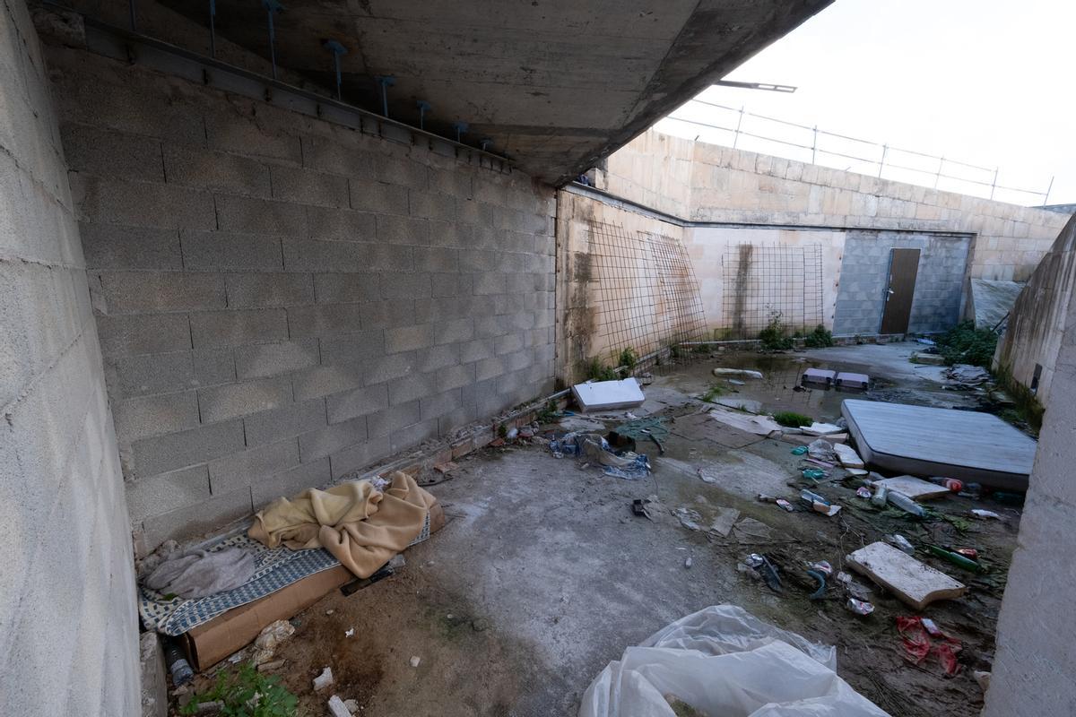 Espacio interior inacabado lleno de suciedad y un colchón con mantas