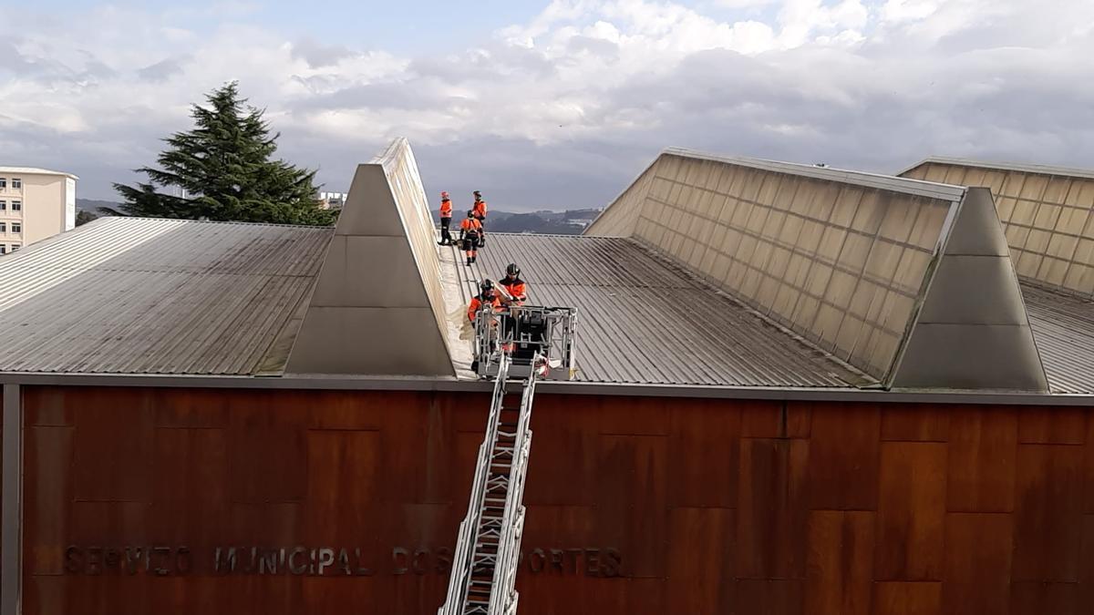 Bomberos trabajan en la cubierta del pabellón deportivo de As Travesas.