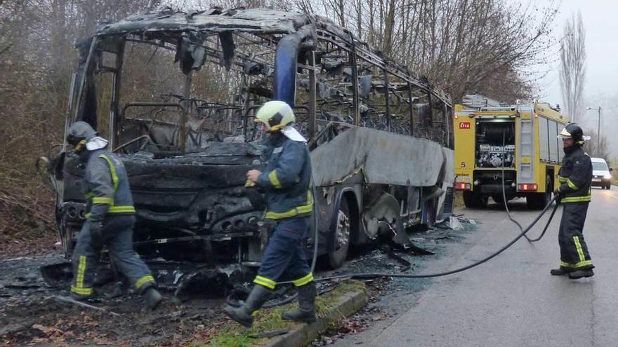 Tres bomberos del SEPA junto al autobús calcinado.