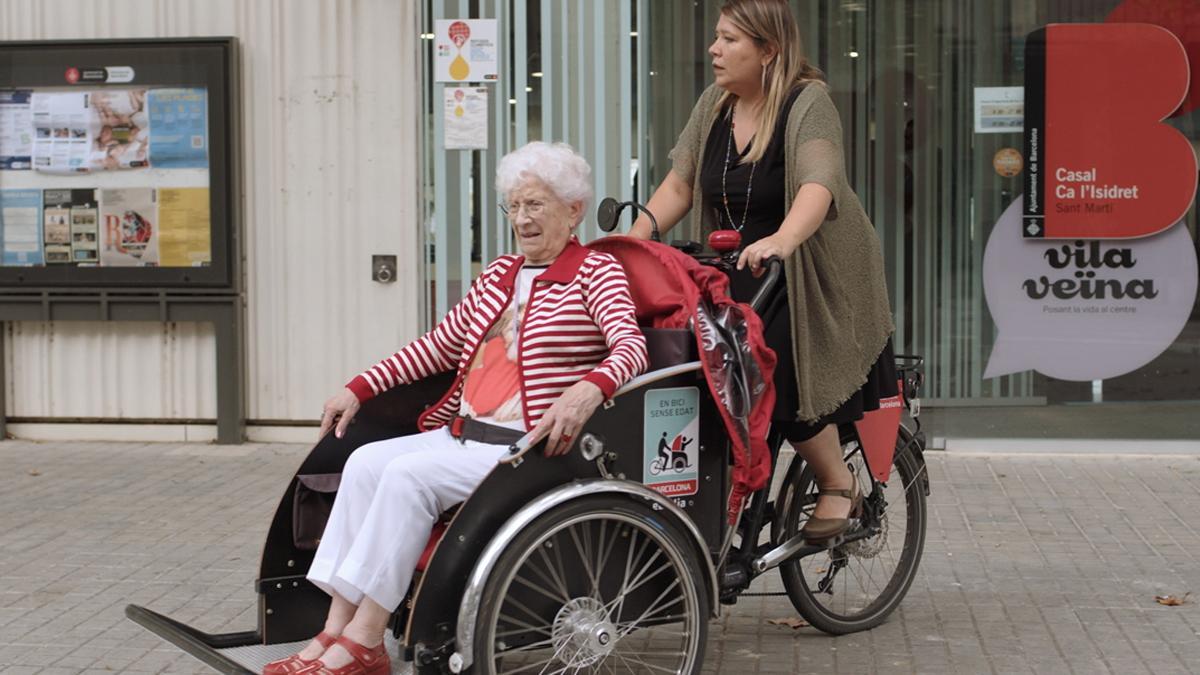 Maria Elisa Ojeda passeja a una persona gran amb la seva bicicleta