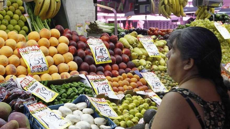 Una mujer frente a un puesto de venta de frutas.