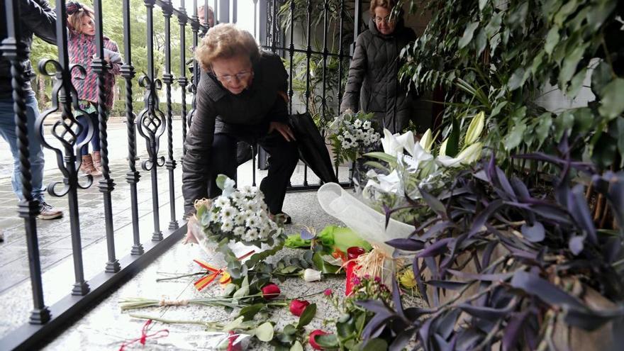 Una mujer deposita flores en el portal donde vivía Barberá.